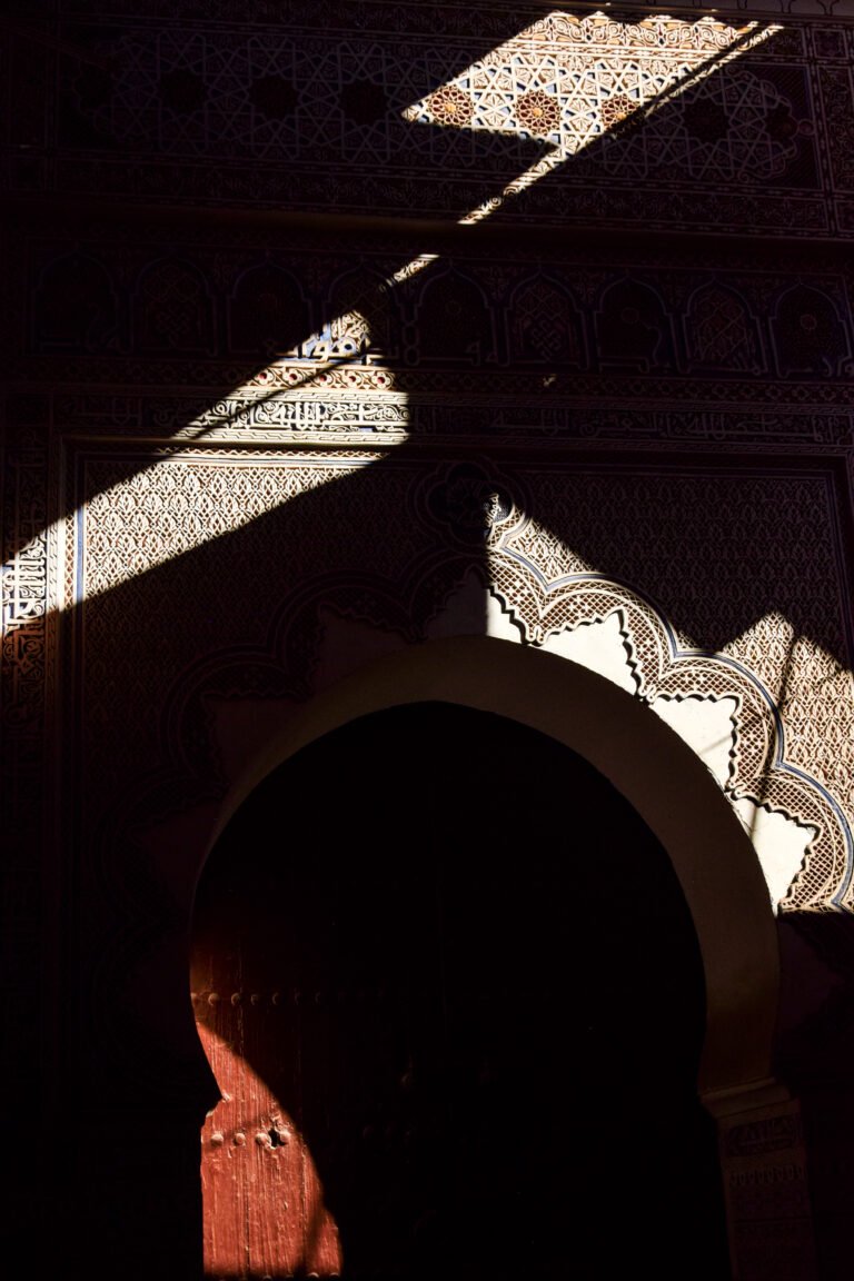 Moroccan patterns on an old gate, partly in shadow and illuminated by sunlight