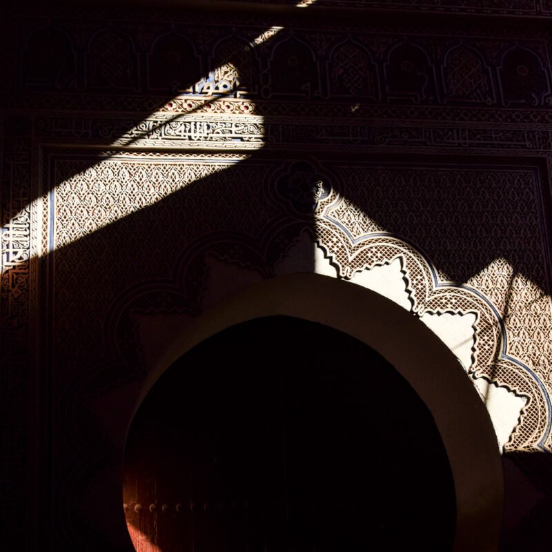 Moroccan patterns on an old gate, partly in shadow and illuminated by sunlight